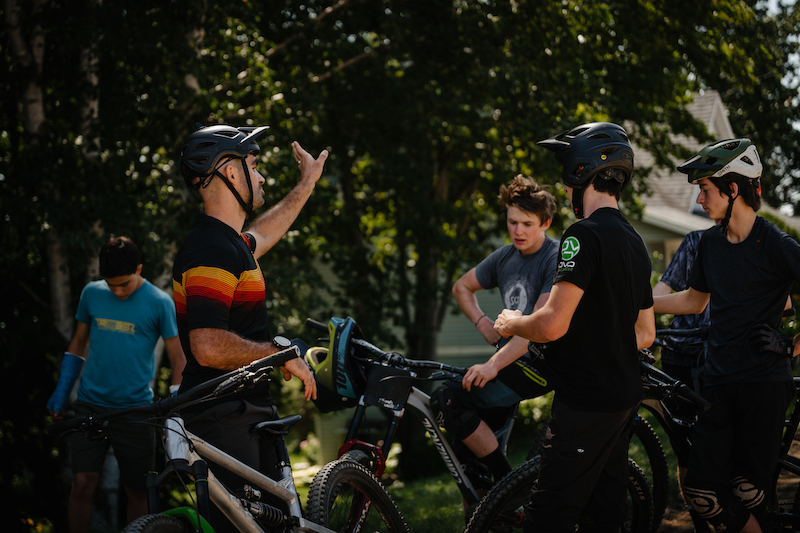 Cycling coach talking to young mountain bike athletes