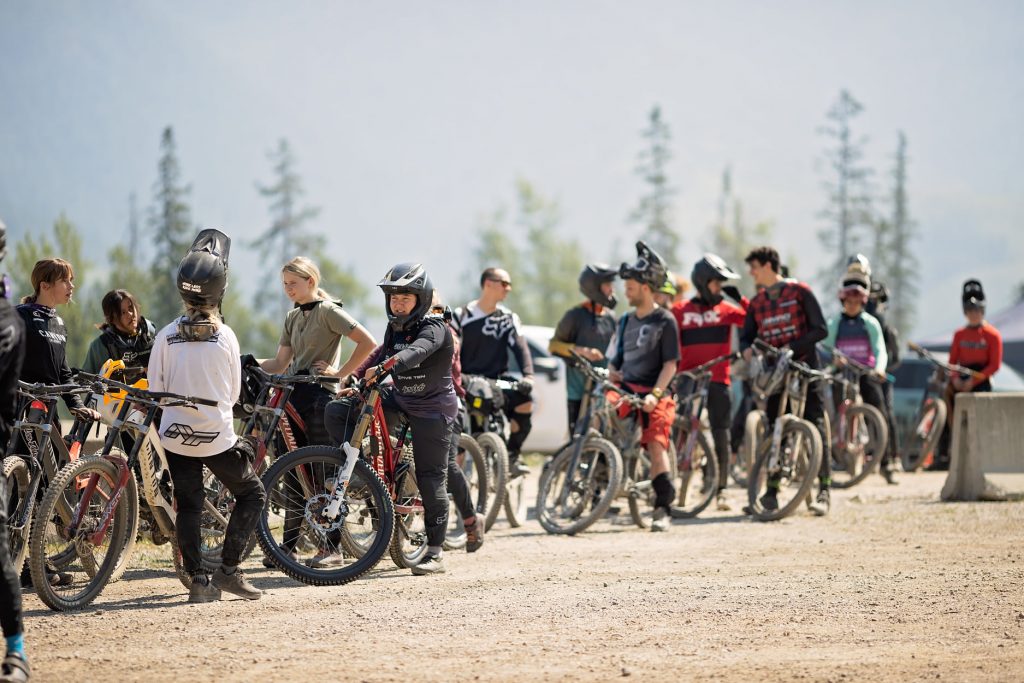Downhill mountain bikers in a long line with their bikes.