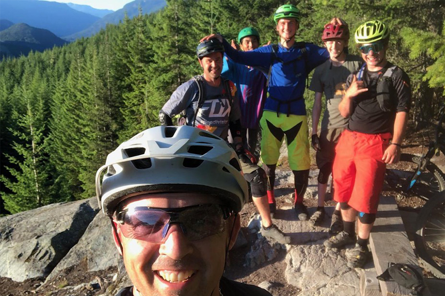 Mountain bike coach and students stop for a photo with scenic mountain views