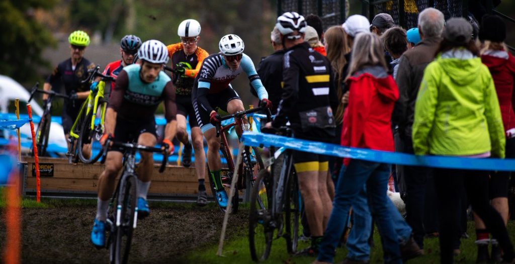 cyclocross bike racers hop over wooden planks on race course