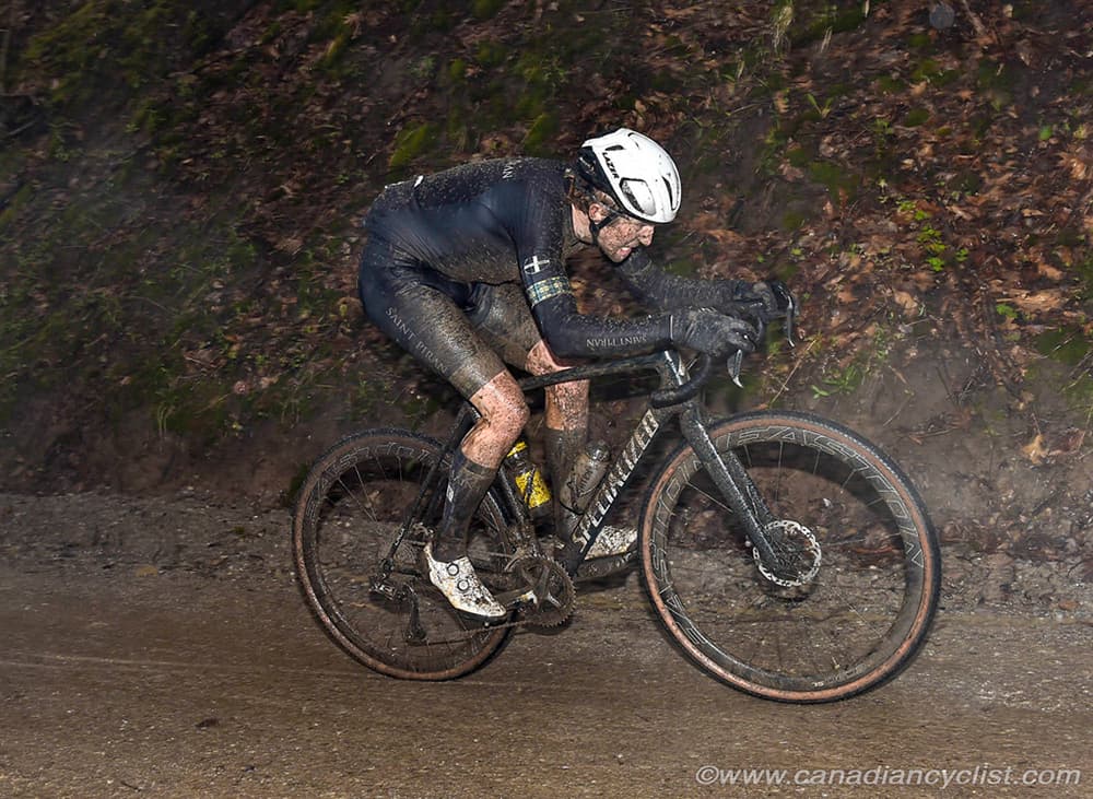 Cyclist covered in mud while riding in wet muddy conditions on gravel path