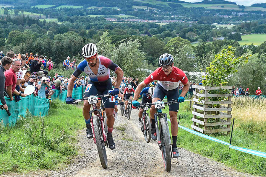 Two mountain bike racers riding side by side up a slope