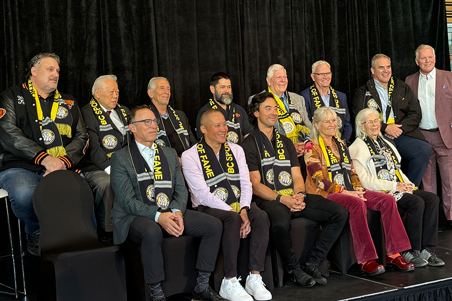 men and women seated in front of a black curtain posing and smiling