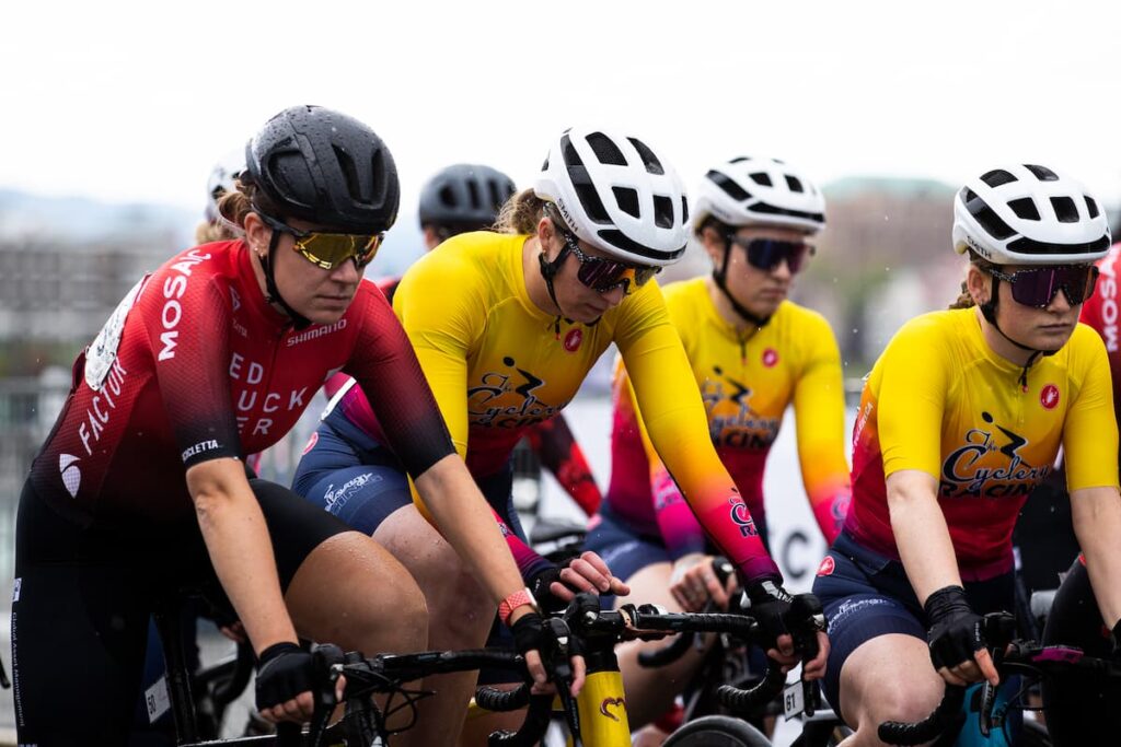 Female road cyclists lined up at a race start line.