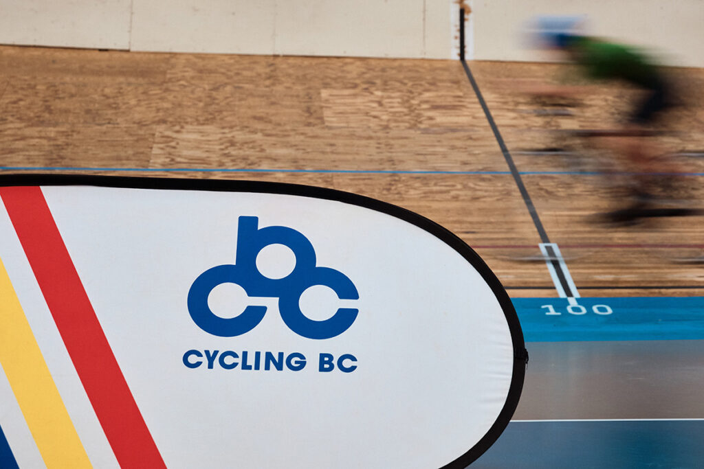 Cycling BC banner in the foreground with a blurred background of a cyclist riding on the velodrome