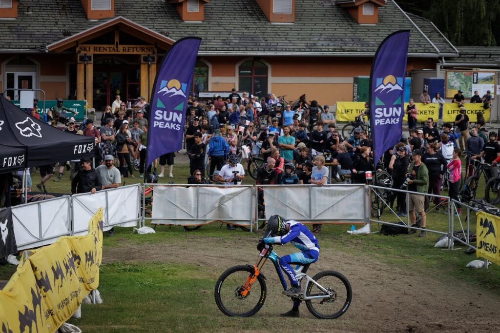 A mountain biker at the end of a run as the crowd looks on.