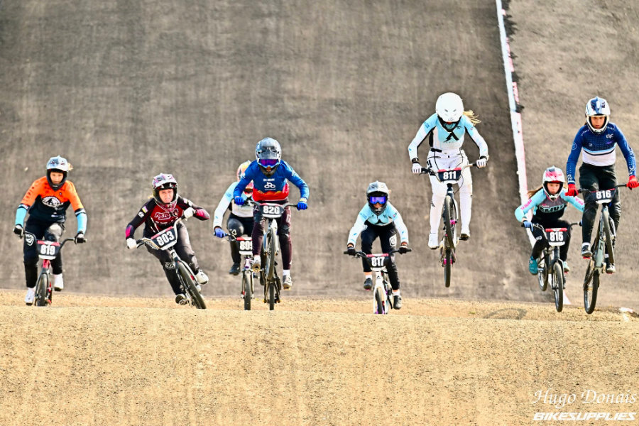 A group of eight BMX riders racing on the track.