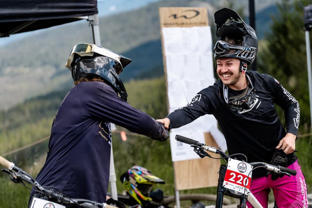 Two mountain bike riders shaking hands and smiling